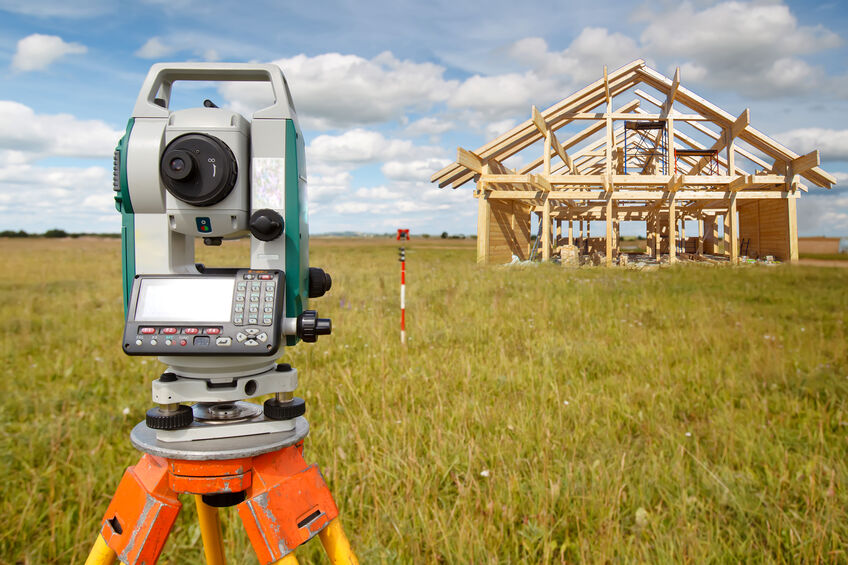 A survey camera, the camera is pointed at a large piece of land with a house frame.